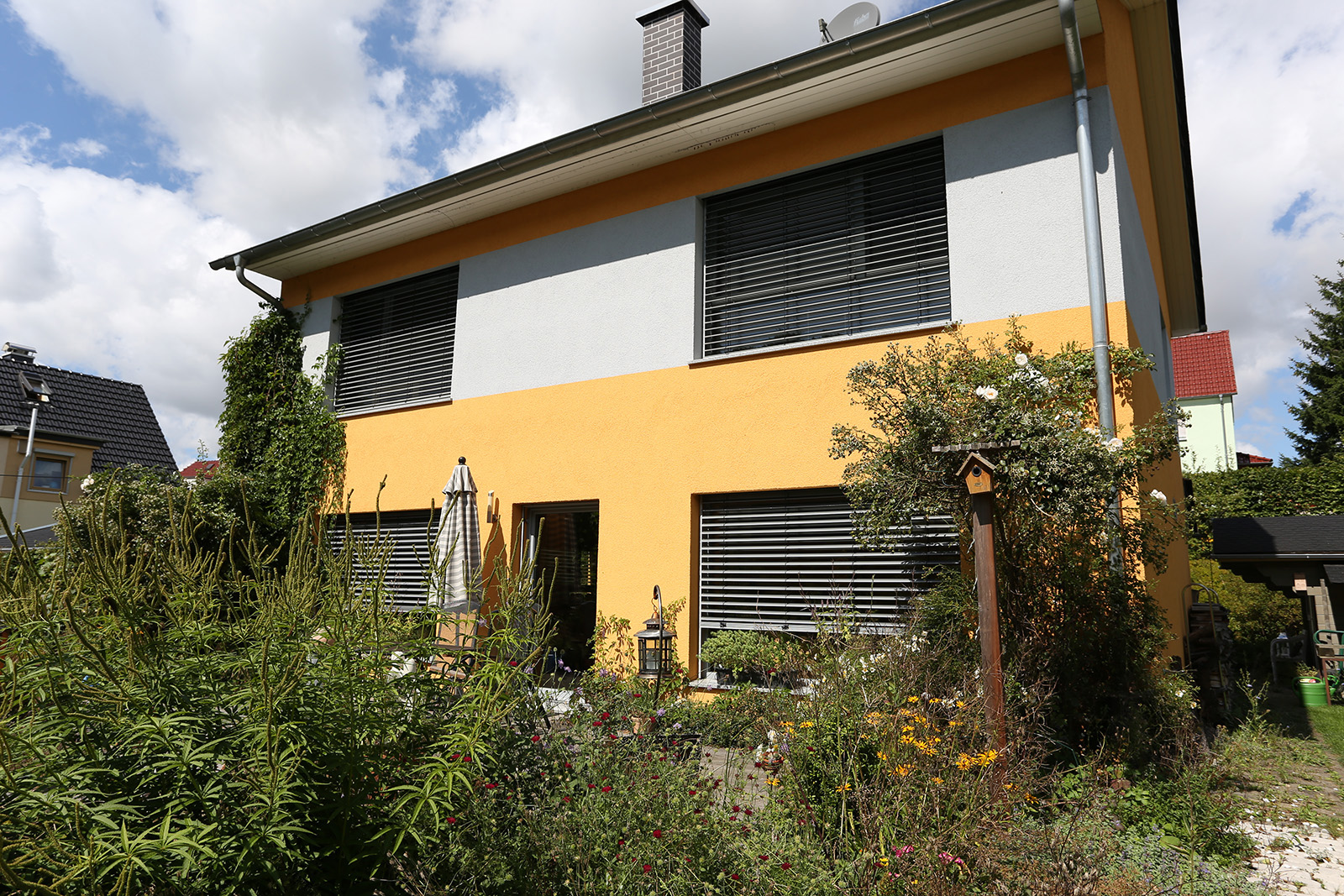 Modernes Einfamilienhaus mit gepflegtem Garten und sonniger Außenansicht.